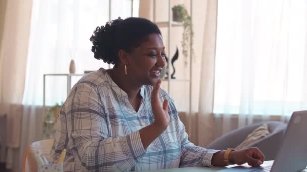 年轻的非洲裔美国女人坐在明亮客厅的办公桌前 在笔记本电脑上视频聊天 — 图库视频影像