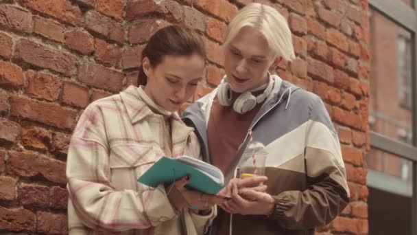 Medellångsam Kaukasiska Par Första Årets Universitetsstudenter Tittar Copybook Och Chatta — Stockvideo