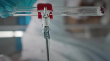 Beyaz erkek mikrobiyolog, koruyucu yüz kalkanıyla laboratuarda kimyasal araştırmalar yaparken, cam test tüpünde tanımlanamayan sıvı maddeleri birleştirirken dikey çekim.