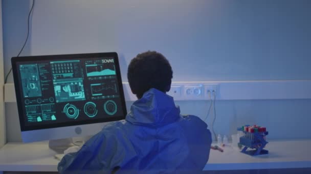 男科学家穿着防护服在计算机上工作的回顾 同时在实验室工作台上对试管中的液体物质进行研究 — 图库视频影像