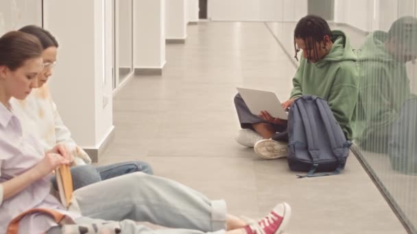 수업을 기다리는 복도에서 바닥에 앉아있는 노트북 컴퓨터에서 후드에 Biracial 학생의 — 비디오