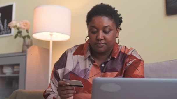 自宅からオンラインショッピングしながら ラップトップでクレジットカードデータを入力する若いカービーブラック女性のウエスト — ストック動画