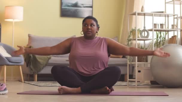 Aktif Giyinmiş Yoga Minderinin Üzerinde Oturmuş Meditasyon Yapan Kıvrımlı Afrikalı — Stok video