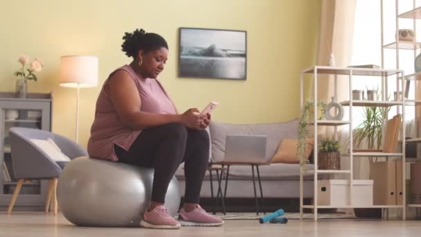 Молода Пишна Чорна Жінка Прокручує Смартфон Сидячи Срібному Ячі Відпочиваючи — стокове відео