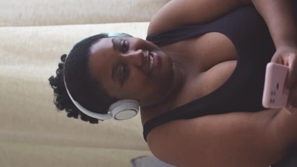 Pionowa Talia Górę Zdjęcia Wesołej Młodej Zakrzywionej Afroamerykanki Słuchawkach Bezprzewodowych — Wideo stockowe