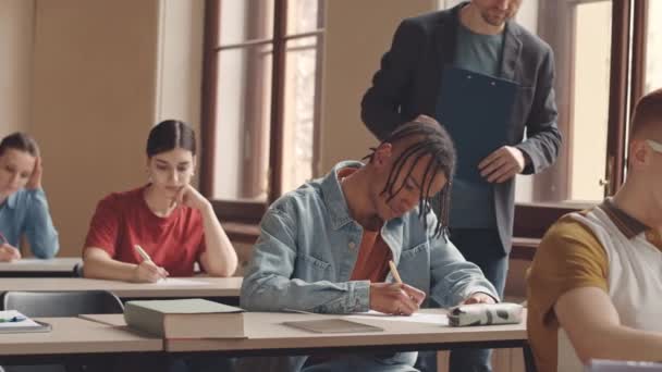 白种人中年大学教授在明亮礼堂帮助学生期末考试的慢动作 — 图库视频影像