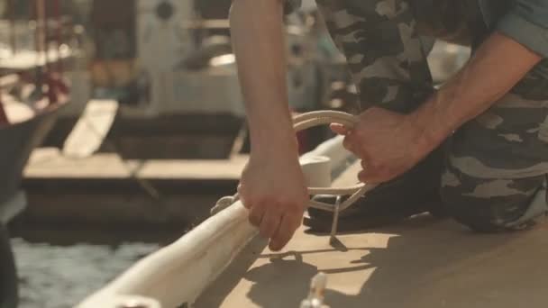 穿着卡其布裤的难以辨认的水手在船上打了个海结 在阳光灿烂的炎热日子呆在港口 — 图库视频影像