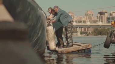 Çeşitli deniz teknisyenleri tekneden denize iniyor ahşap salda adım adım duruyorlar.
