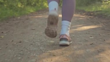 Spor ayakkabılı, parkta koşu yapan, tanınmayan bir kadının alt kesimi.