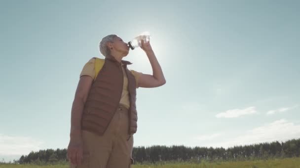 Niski Kąt Ujęcia Starszej Azjatki Pijącej Wodę Stojącej Pod Błękitnym — Wideo stockowe