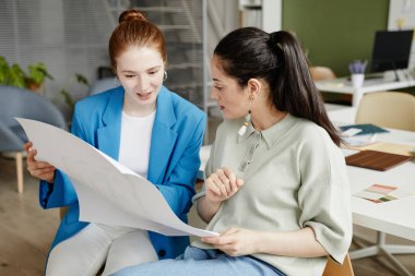 Ofiste otururken inşaat projesinin planını inceleyen iki bayan meslektaşım var.