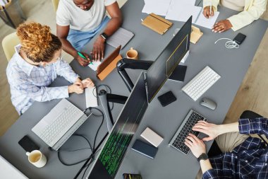 Bilgisayar monitörleriyle masada oturan yeni yazılımın geliştirilmesini tartışan bir grup programcının yüksek açılı görünümü