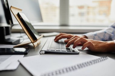 Genç programcının masadaki dijital tabletin önünde otururken klavyede kod yazmak için daktilo yazarken yakın plan görüntüsü