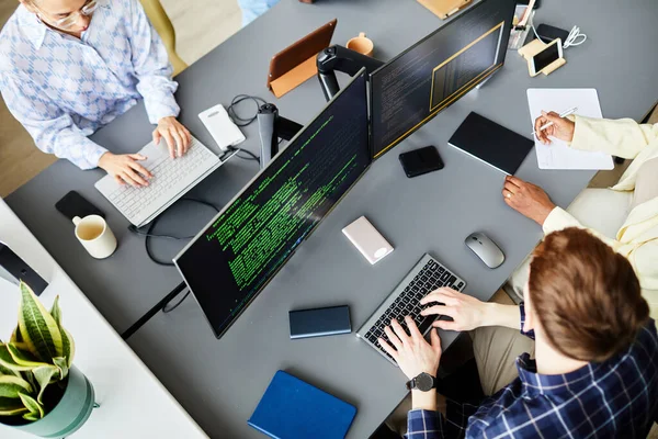 stock image High angle view of group of programmers sitting at table in front of computer monitors and working with codes