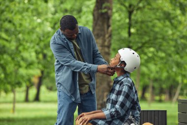 Afrikalı baba, maçtan önce oğluna kask takıyor.