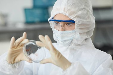 Laboratuvarda kan örneklerini incelerken koruyucu giysili bir kadın portresi.