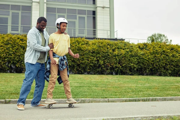 Afrikansk Glad Pappa Knuffar Sin Son Medan Han Står Skateboard — Stockfoto