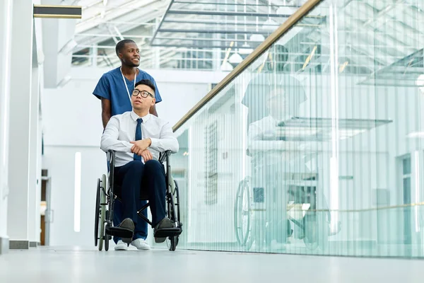 非洲裔美国医生在现代诊所帮助轮椅人的全长画像 复制空间 — 图库照片