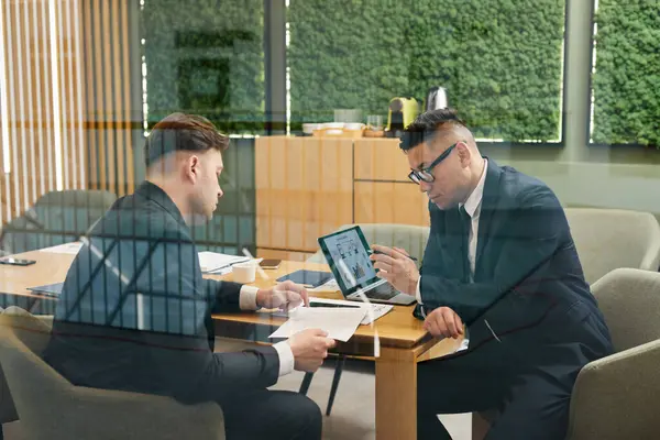 会議室で会合し ガラス壁の背後でプロジェクト戦略を計画する2人のビジネスマン — ストック写真