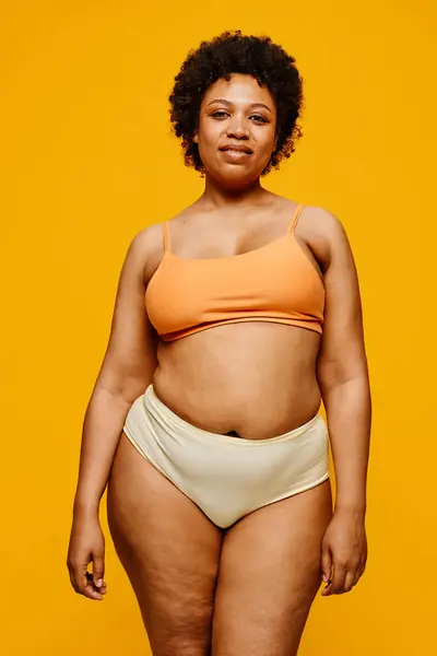黄色背景下身穿内裤的自信黑人妇女的垂直肖像 — 图库照片