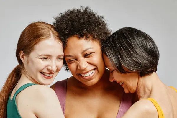 Candid portrait of three diverse young women laughing happily together