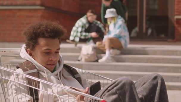 Slowmo Cool Biracial Adolescente Menino Rolando Smartphone Enquanto Sentado Carrinho — Vídeo de Stock