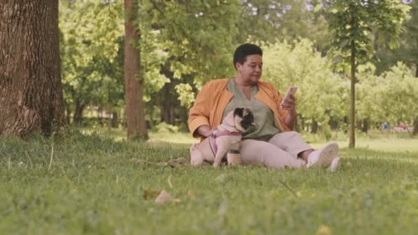 Slowmo Mid Adult Black Woman Pug Scrolling Smartphone Sitting Grass — Stock Video