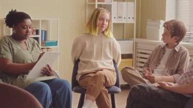 Ofisinde bir grup genç ile çalışırken iletişim teknikleri deneyen siyahi kadın psikoloğu.