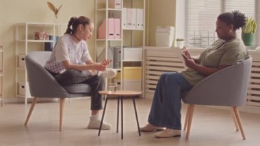 Kafkas ergen kız ve siyahi kadın psikoloji uzmanının yan görüşü. Parlak modern ofiste oturmuş sohbet ediyorlar.