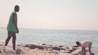 Afrika kökenli Amerikalı baba ve küçük kızın yazın kumlu sahilde frizbiyle oynamaları.