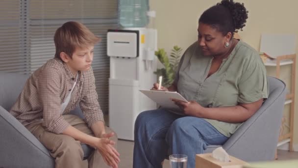 在明亮的现代办公室里与非裔美国女性心理学专家单独治疗的可悲的白人男生的中速 — 图库视频影像
