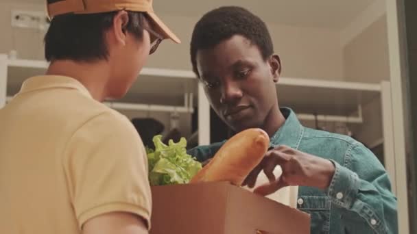 Jonge Afro Amerikaanse Man Ontvangt Boodschappenbezorging Door Jonge Aziatische Mannelijke — Stockvideo