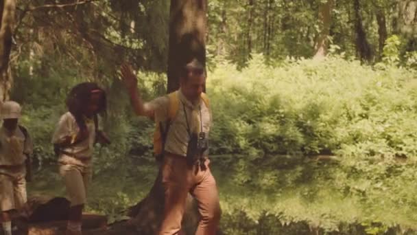 Zróżnicowane Dzieci Mundurach Harcerskich Podążające Swoim Przywódcą Podczas Wędrówki Lesie — Wideo stockowe