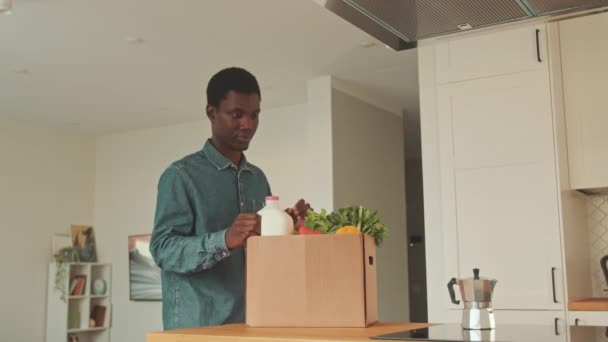 年轻黑人男子在公寓里打开装有杂货的纸板箱中的镜头 — 图库视频影像