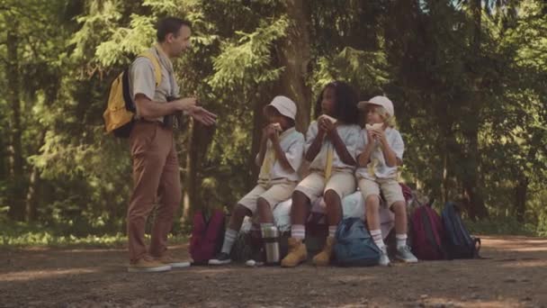Полнометражный Снимок Разнообразной Группы Детенышей Скаутов Сидящих Своих Рюкзаках Обедающих — стоковое видео