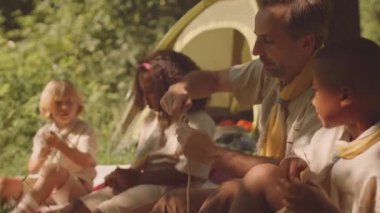 Orta yaşlı beyaz erkek izci. Çeşitli yavrular. Yaz ormanlarında birlikte kamp yaparken bağlarını koparmak için.