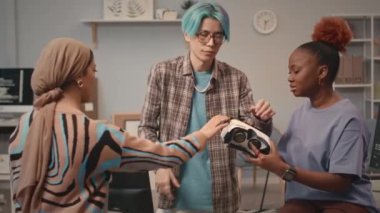 Modern ofiste çalışan çok ırklı VR oyun geliştiricileri, VR gözlüklerini test ediyorlar ve tartışıyorlar