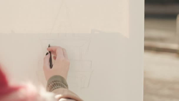 鉛筆で屋外のキャンバスにタワーを描くピンク髪の少女の肩の上に — ストック動画