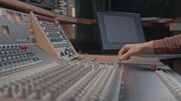 音楽制作中にコンソールをミキシングして認識できない男性スタジオオオペレーターのクロップショット — ストック動画
