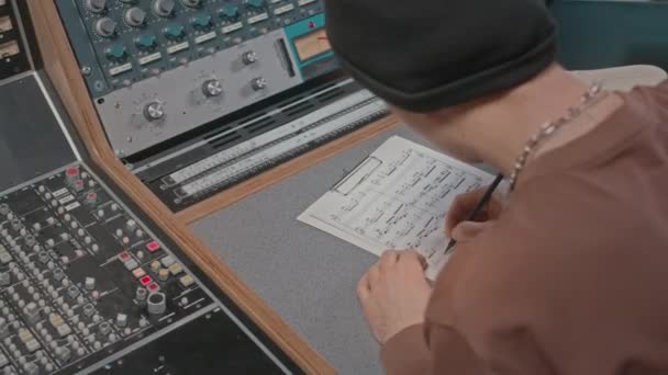 プロのレコードスタジオでワークステーションに座って音楽を書く若い男性作曲家 — ストック動画