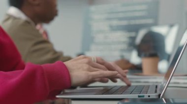 Ofiste çalışırken dizüstü bilgisayarda yazan kırmızı sweatshirt giyen tanınmayan genç programcının el kesimi.