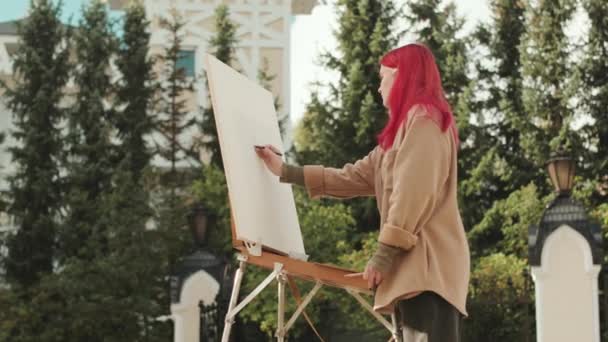 夏日公园的画布上画着色彩艳丽的红头发的年轻女子的中景照片 — 图库视频影像