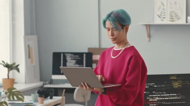 在现代写字楼里 用笔记本电脑对着相机摆出一副染成蓝色头发的年轻亚洲人的中影 — 图库视频影像