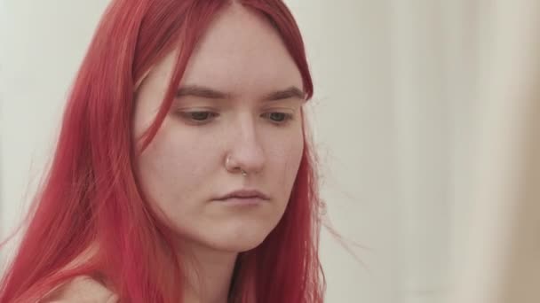 屋外のキャンバスに明るい赤い髪と鼻のピアス絵を持つ白人の若い女性のショットでズーム — ストック動画