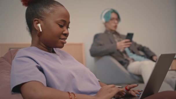Νεαρή Μαύρη Γυναίκα Ασύρματα Ακουστικά Που Χρησιμοποιεί Φορητό Υπολογιστή Ενώ — Αρχείο Βίντεο