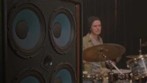 前景にスタジオモニター付きプロサウンドスタジオでドラムを演奏する若いミュージシャン — ストック動画