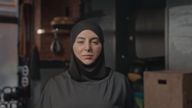 Boks kulübünde kameraya poz veren siyah tesettürlü genç Müslüman kadın portresi