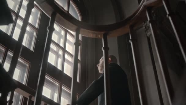 黑暗的天主教堂中穿着西服的中年白种人牧师站在窗边的低角度中肖像画 看着镜头 — 图库视频影像