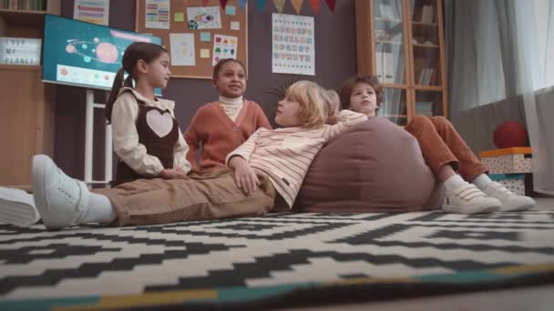 Vier Multiethnische Vorschulkinder Sitzen Und Liegen Auf Einem Teppich Einem — Stockvideo