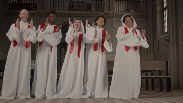 五个身穿白色长袍的多民族教会唱诗班成员在旧天主教堂里一排排地拍手歌唱 — 图库视频影像